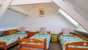 Um quarto de dormitório com três camas de madeira, um pequeno armário e um quadro na parede.