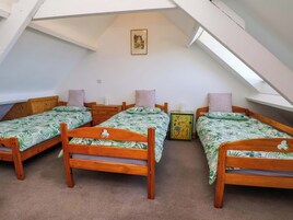 Un dormitorio con tres camas de madera, un mueble pequeño y un cuadro en la pared.
