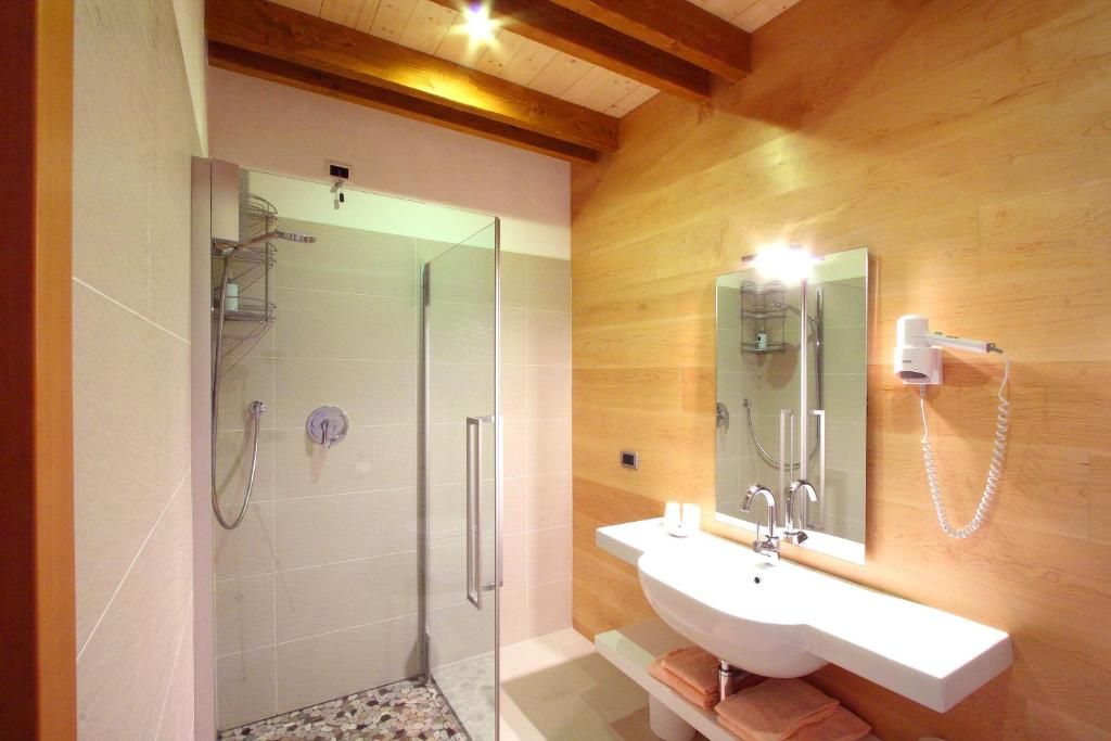 A modern bathroom with a glass-enclosed shower, a white sink, and a mirror with a built-in hairdryer.
