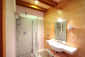 A modern bathroom with a glass-enclosed shower, a white sink, and a mirror with a built-in hairdryer. - Affittacamere Alle Trote (SÙTRIO)