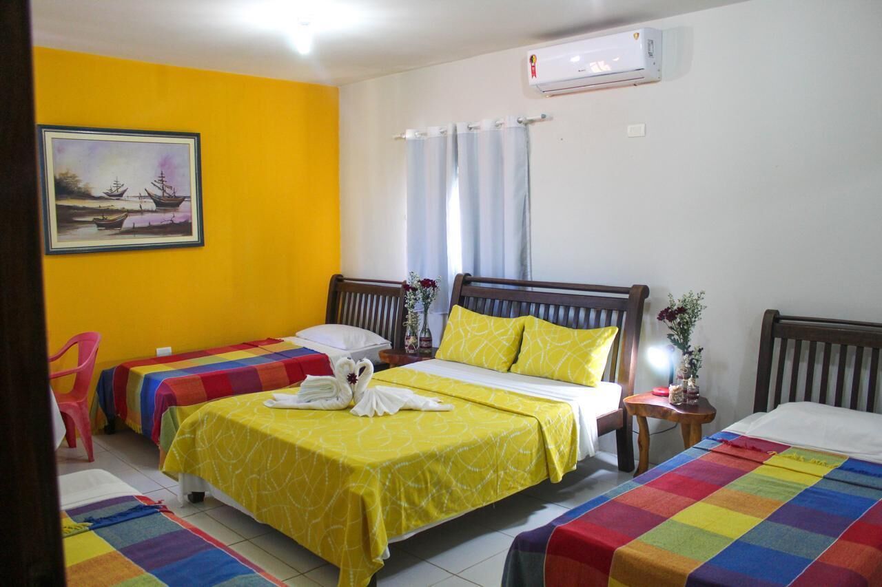 A hotel room with two beds, a painting on the wall, an air conditioner, and a window with curtains.
