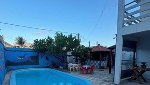 Une piscine entourée d’une terrasse en pierre, avec des chaises et des tables.