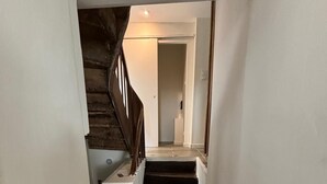 Eine Treppe mit Holzboden und Handlauf, die zu einem Raum mit weißen Wänden und einer Tür führt.