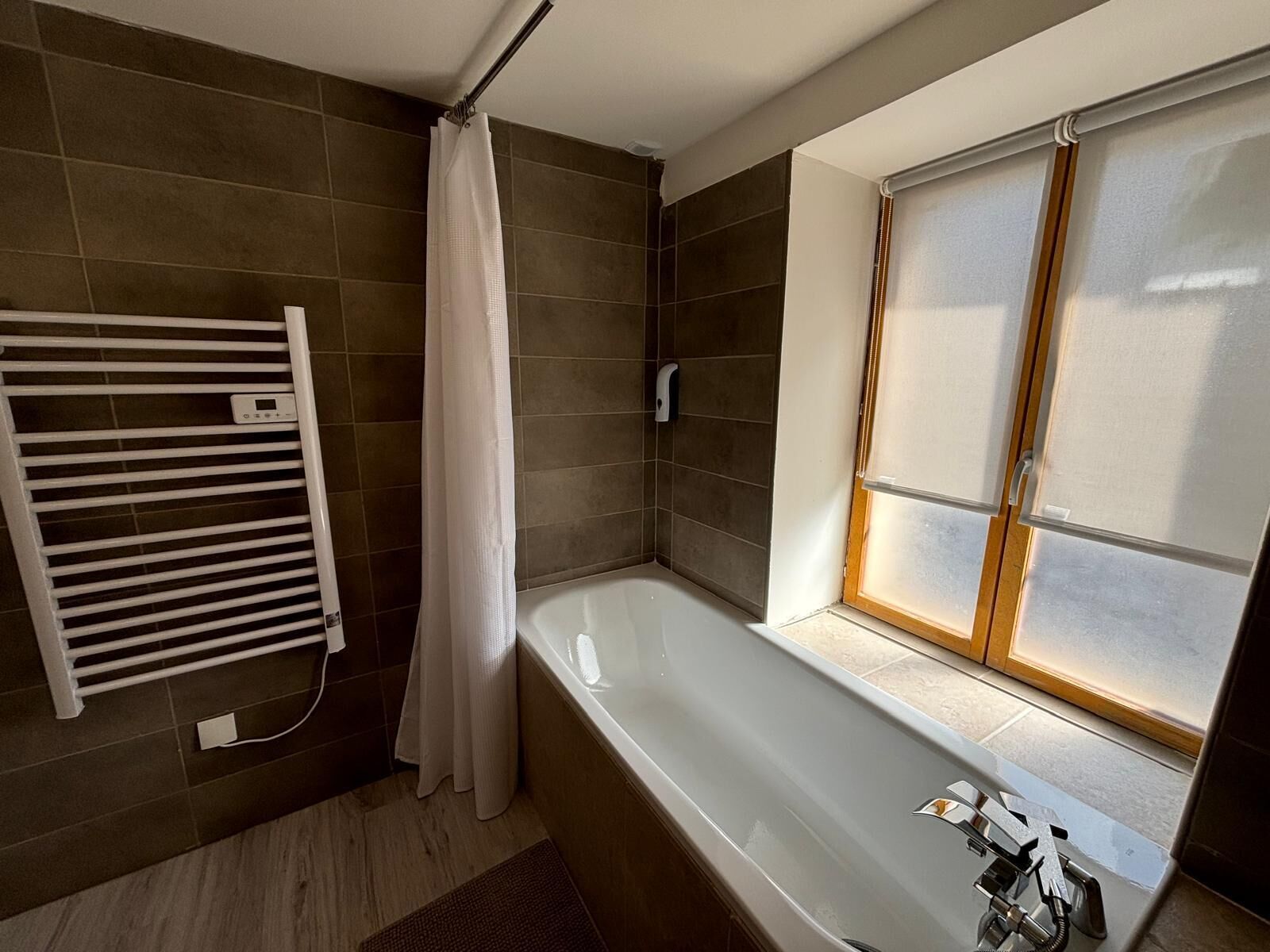 Ein modernes Badezimmer mit Badewanne, Fenster, Handtuchhalter und Duschvorhang.