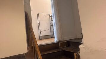 A staircase with a wooden handrail, a metal banister, and a white wall.