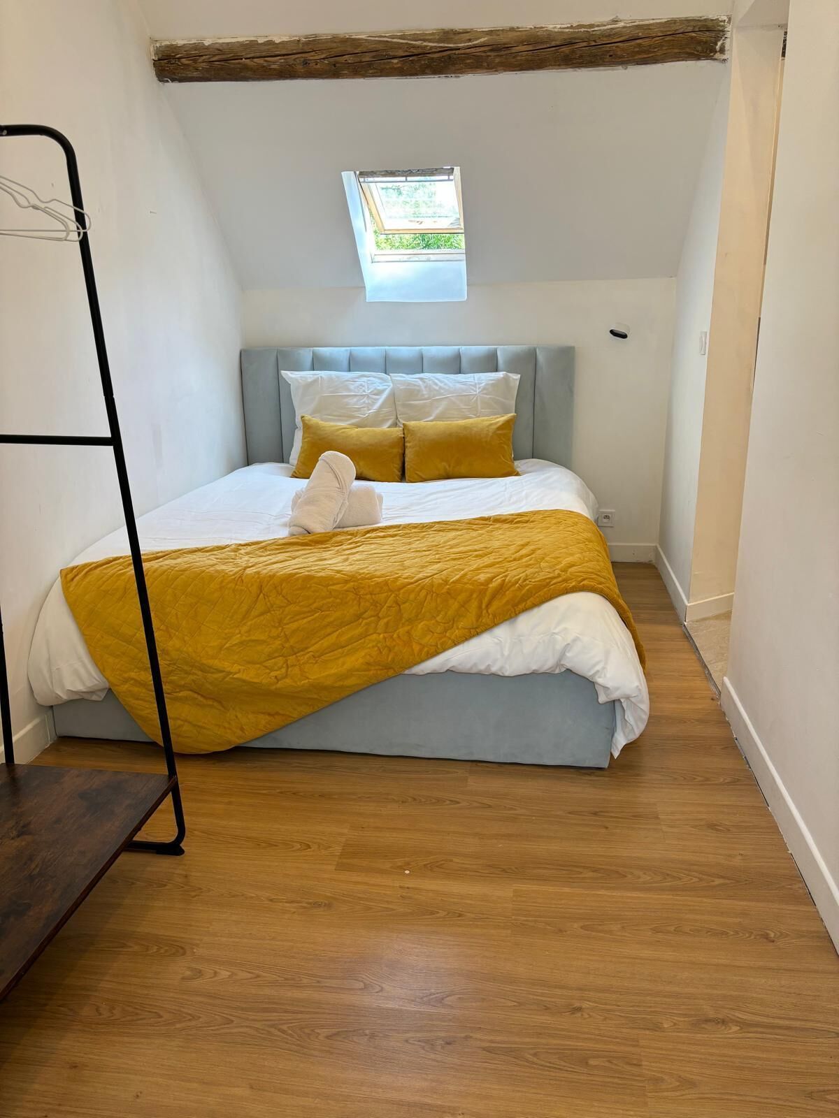 A bedroom with a bed, a window, and a wooden floor.