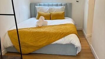 A bedroom with a bed, a window, and a wooden floor.
