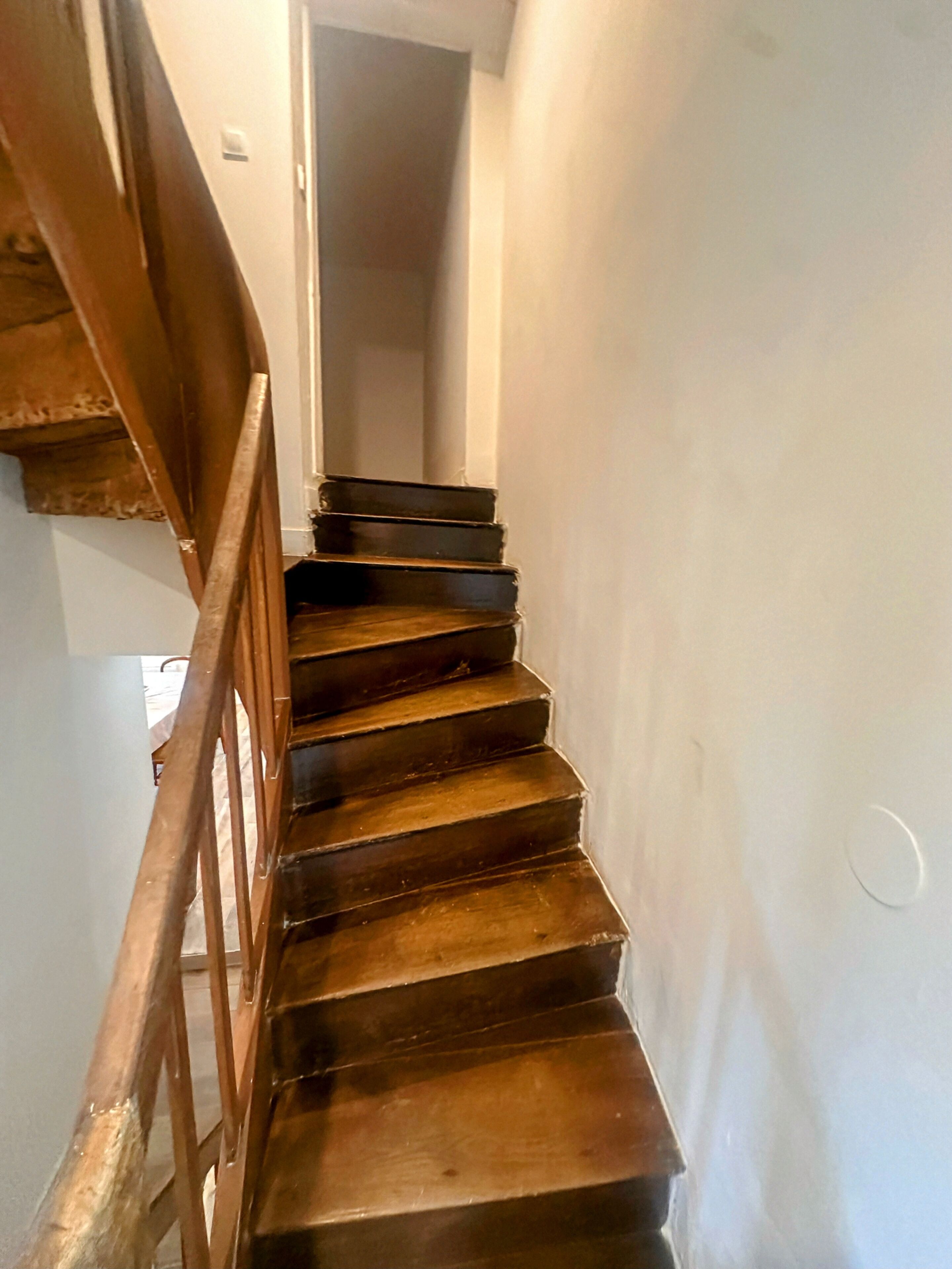 Una escalera de madera con barandilla que lleva a una puerta.