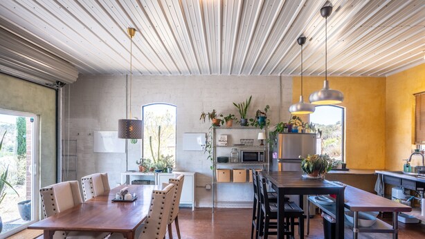 Eine moderne Küche mit Essbereich, ausgestattet mit einem Holztisch, Stühlen und Pendelleuchten.