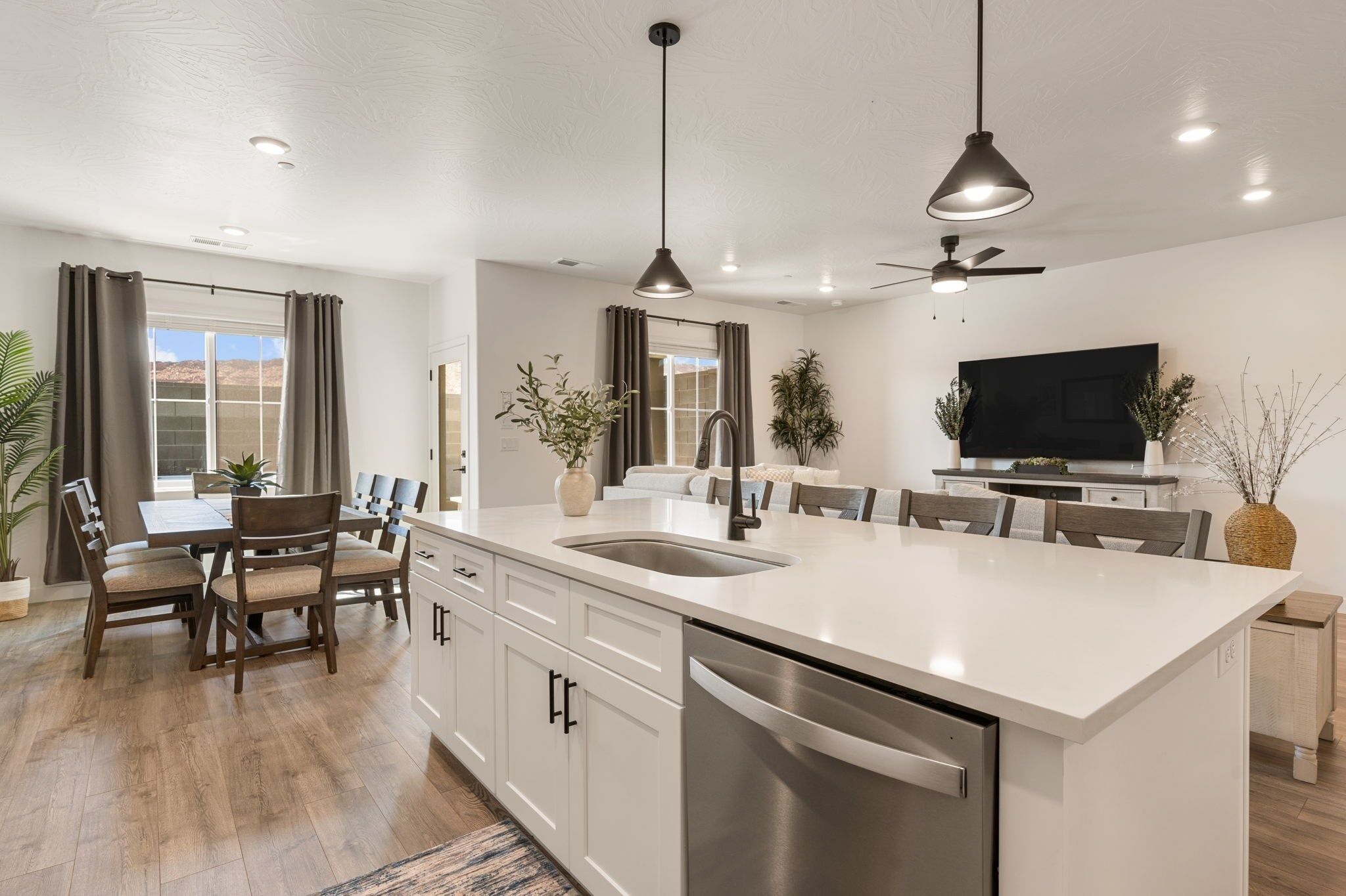 A modern kitchen with a central island, white cabinetry, and a built-in dishwasher.
