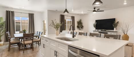 A modern kitchen with a central island, white cabinetry, and a built-in dishwasher.