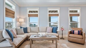A living room with a sectional sofa, a coffee table, a chair, and a small table with a lamp. - The Big Fish On Redfish 4 Bedroom Home (Port Bolivar)