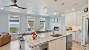 A modern kitchen with a large island, white cabinetry, and a view to the outside. - The Big Fish On Redfish 4 Bedroom Home (Port Bolivar)