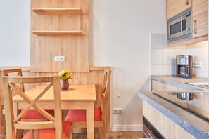 Une cuisine avec des meubles de rangement en bois, un four à micro-ondes, une machine à café et une table à manger avec des chaises.