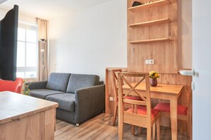 Un salon moderne avec un canapé gris, une table à manger en bois et des chaises.