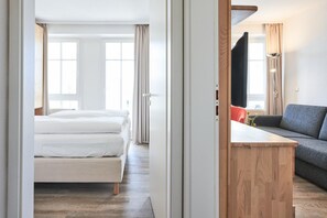Une pièce comprenant un lit, un canapé, une table en bois et une fenêtre avec des rideaux.