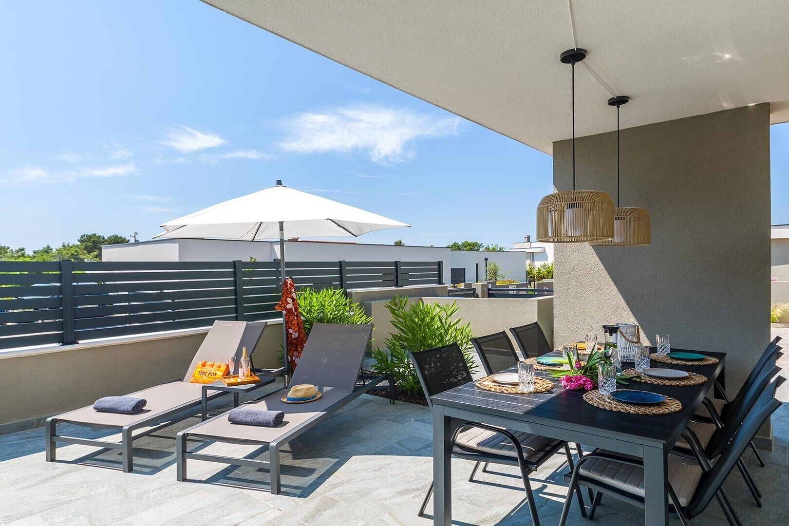 A rooftop terrace with lounge chairs, a dining table, and a pergola.