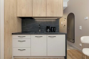 Eine moderne Küche mit schwarzem Marmorarbeitsplatz, Holzschränken und einer integrierten Kaffeemaschine.