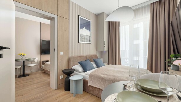 Ein modernes Hotelzimmer mit einem Bett, einem Nachttisch und einer Essecke mit Tisch und Stühlen.