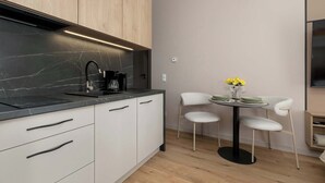 Eine moderne Küche mit schwarzem Arbeitsplatz, weißen Schränken und einem Essbereich mit rundem Tisch und zwei Stühlen.