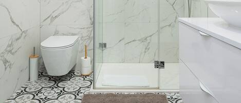 Un baño moderno con ducha de vidrio, inodoro y lavamanos.