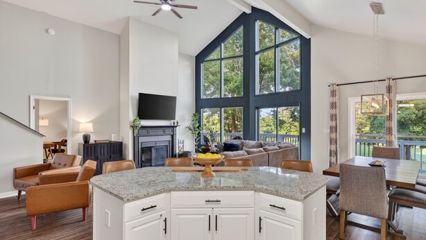 A spacious living area with a large kitchen island, a fireplace, and a dining area with a view of the outdoors. - Fairway to Heaven: A-frame Retreat with Hot Tub, Arcade, Golf and More. Dogs OK. (Hedgesville)