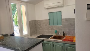 Una cocina con pileta, encimera, alacenas y un equipo de aire acondicionado.