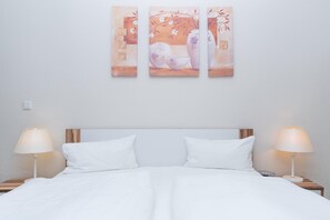 A neatly made bed with white linens, two bedside lamps, and a wall-mounted artwork above. - Geschmackvoll Eingerichtete Ferienwohnung fur 4 im Seepark Sellin (Sellin)