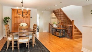 A dining area with a wooden table and chairs, a chandelier, and a staircase with wooden railings. - Charming, Family Friendly 3 bedroom House with Home Theatre near airport/transit (Toronto)
