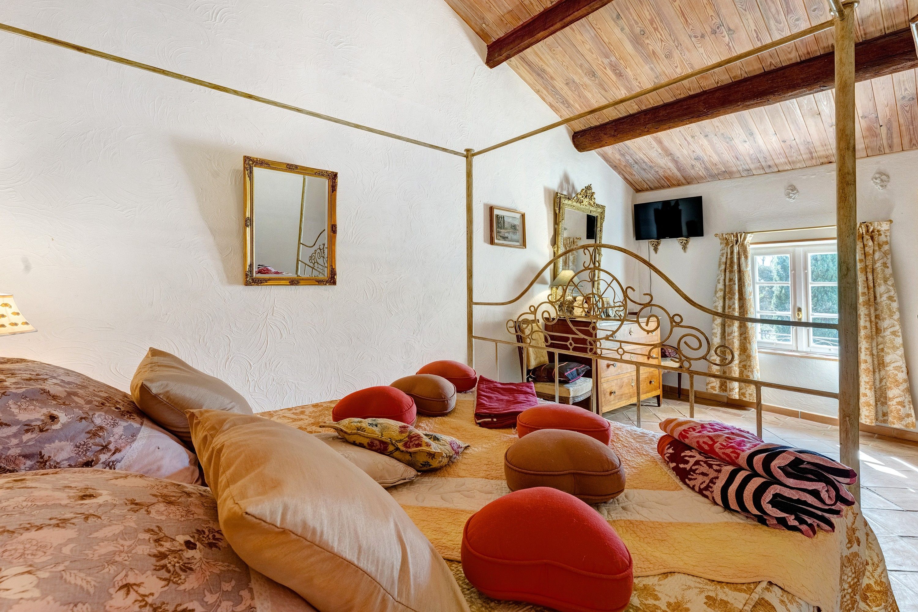 A bedroom with a bed, pillows, a dresser, a mirror, and a television.