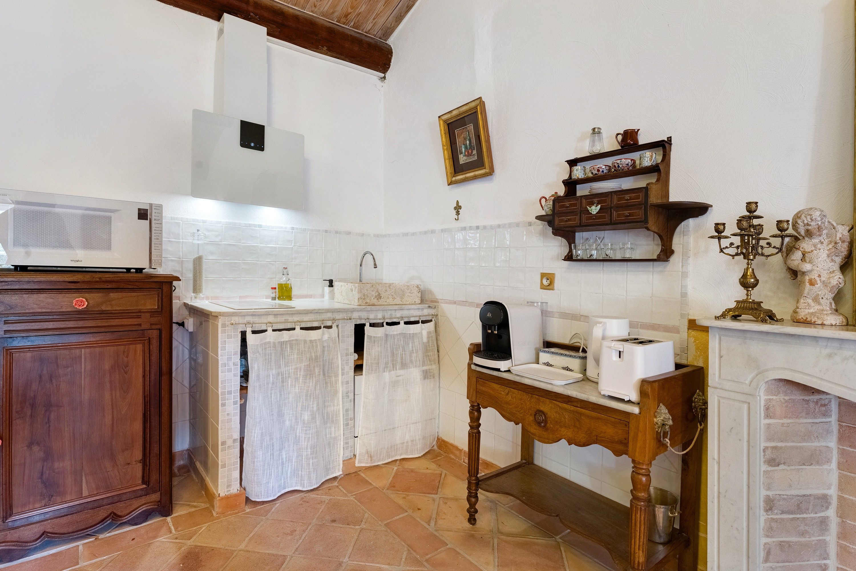 A kitchen with a microwave, coffee maker, toaster, and a decorative statue.