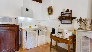 A kitchen with a microwave, coffee maker, toaster, and a decorative statue.
