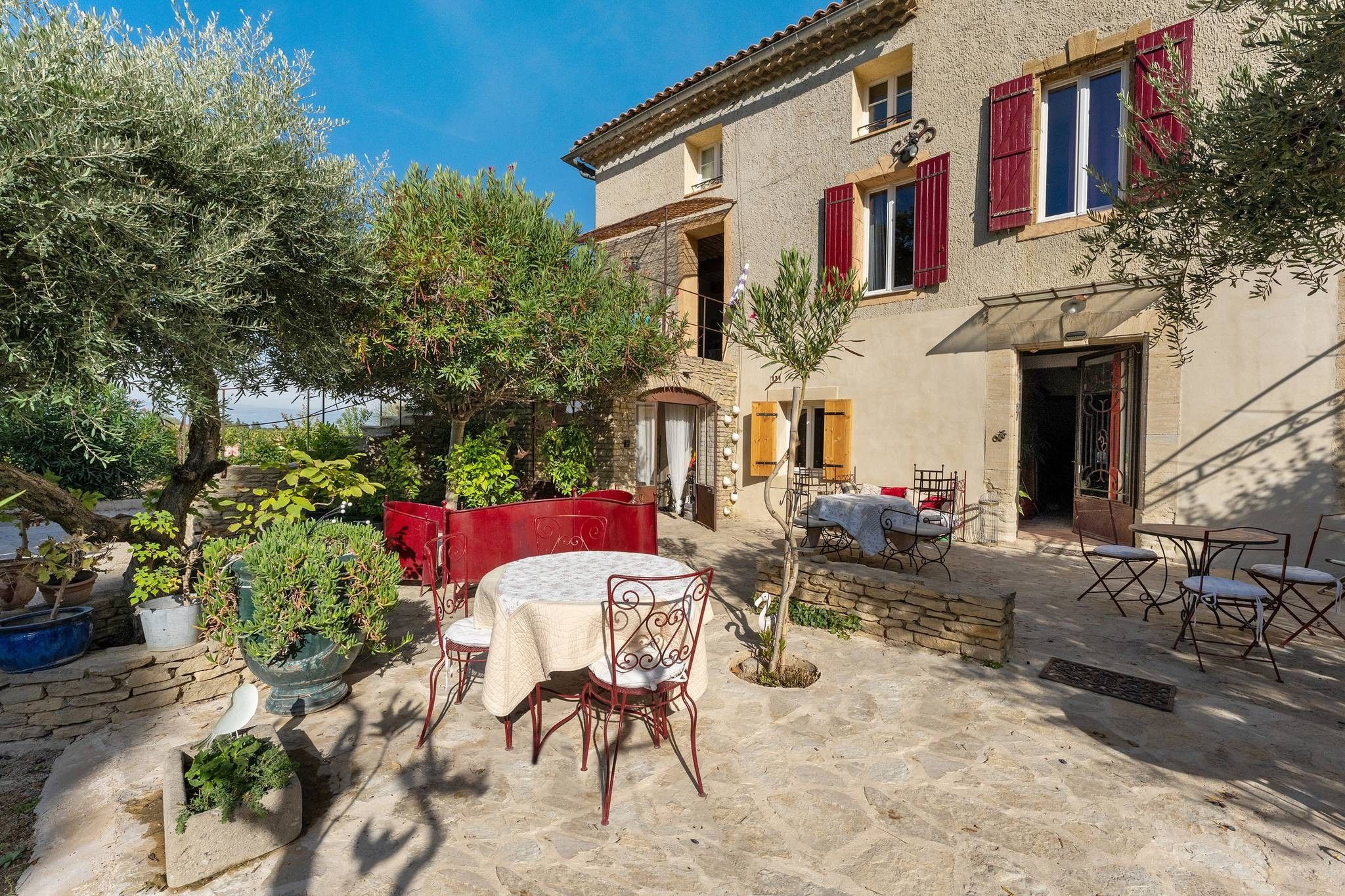 A courtyard with a table and chairs, a red sofa, and potted plants.