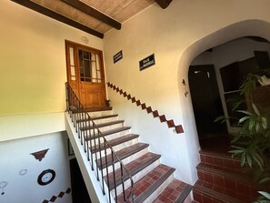 Una escalera con una puerta de madera, un cartel que dice 'RUE DE LA PASSERELLE' y un reloj en la pared.