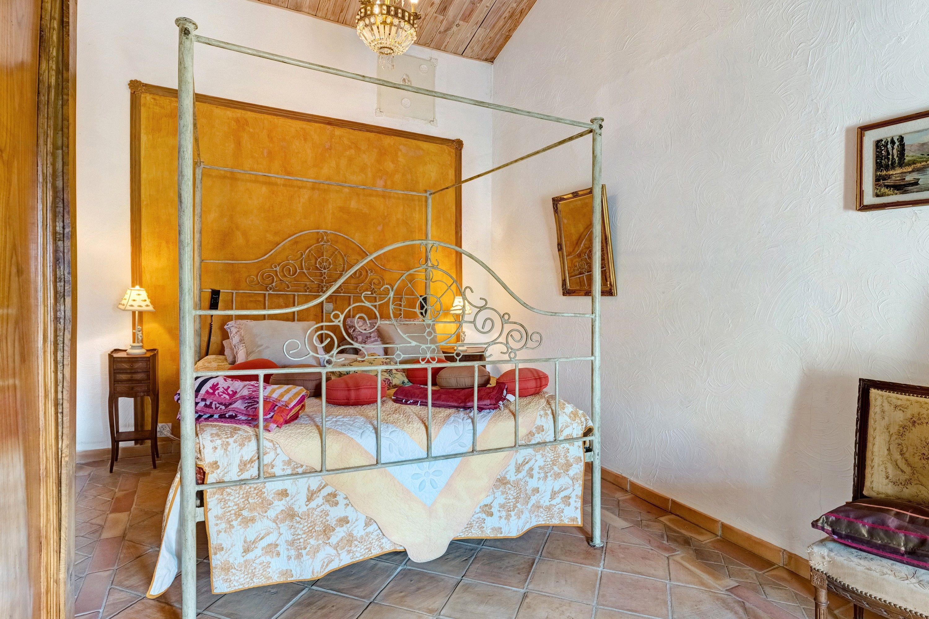 Een hemelbed met een metalen frame, een houten hoofdbord en een bed met een dessin.