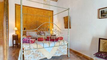 Een hemelbed met een metalen frame, een houten hoofdbord en een bed met een dessin.