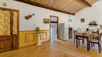 A spacious kitchen with a dining table, chairs, and a refrigerator.