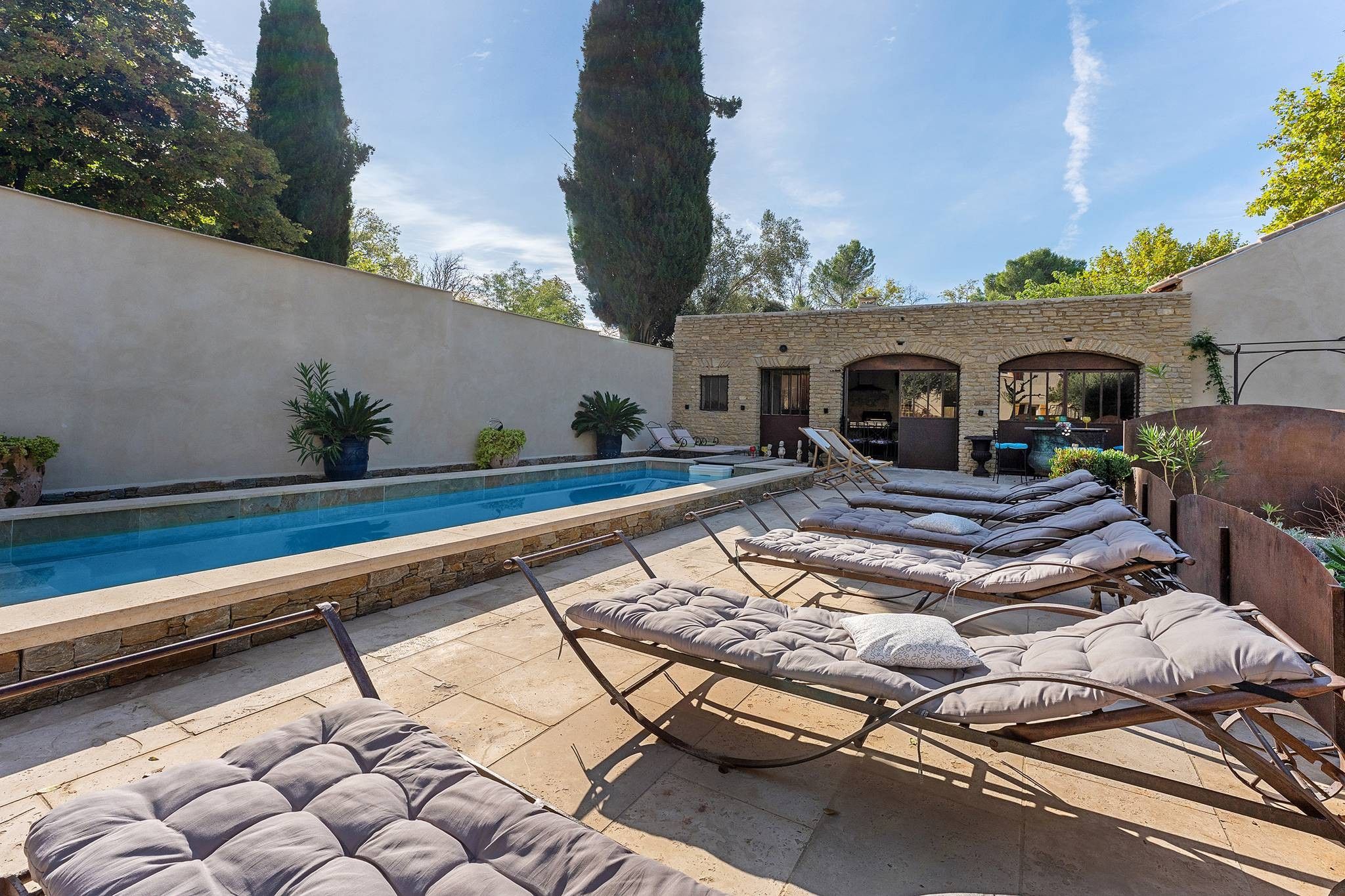 Un espace piscine avec des chaises longues et un mur en pierre.