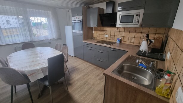 Ett kompakt kök med en matplats, ett kylskåp, en mikrovågsugn och en diskho.