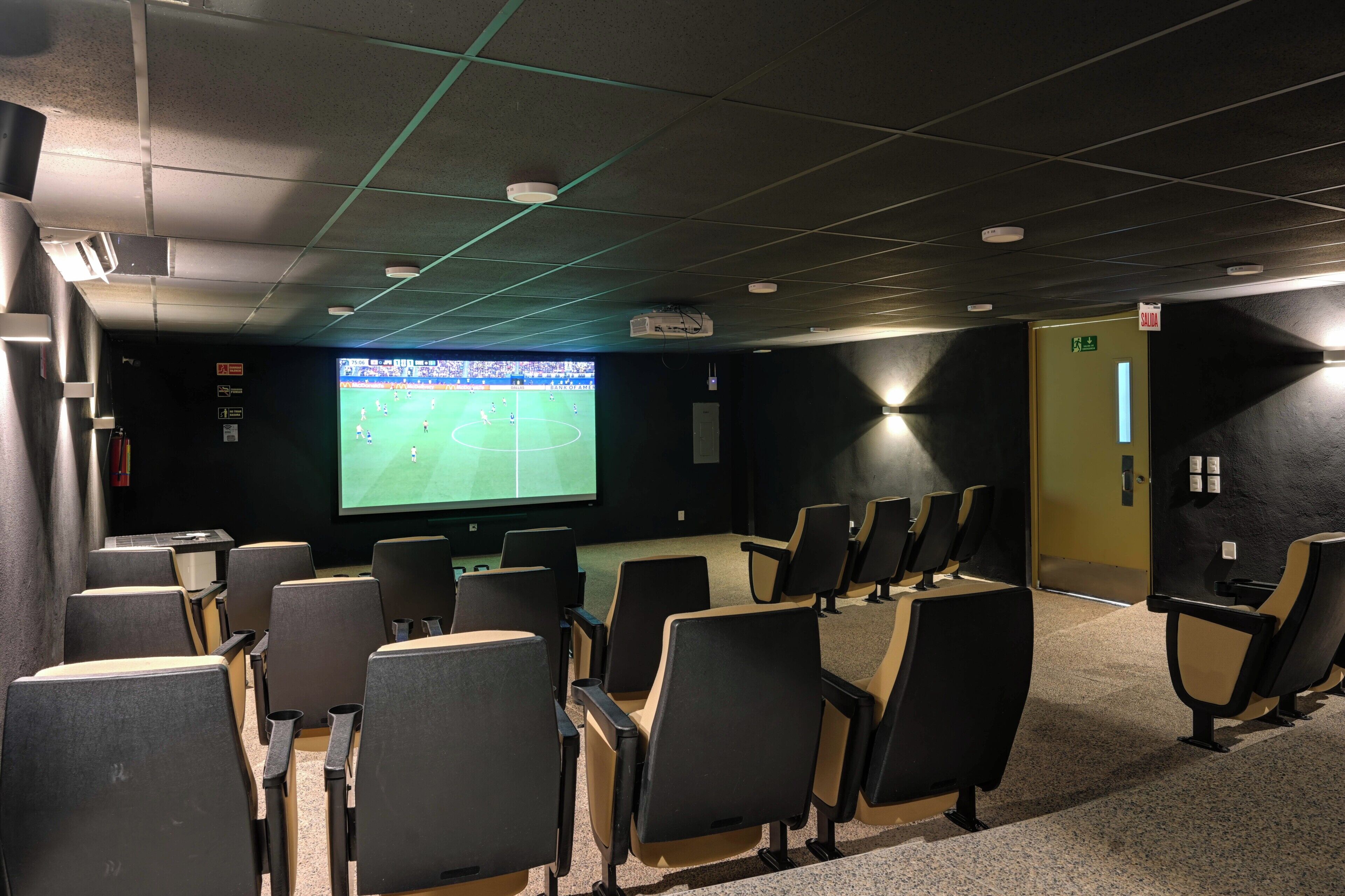 Une salle de cinéma avec des rangées de sièges, un grand écran et un projecteur.