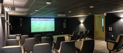 Une salle de cinéma avec des rangées de sièges, un grand écran et un projecteur.