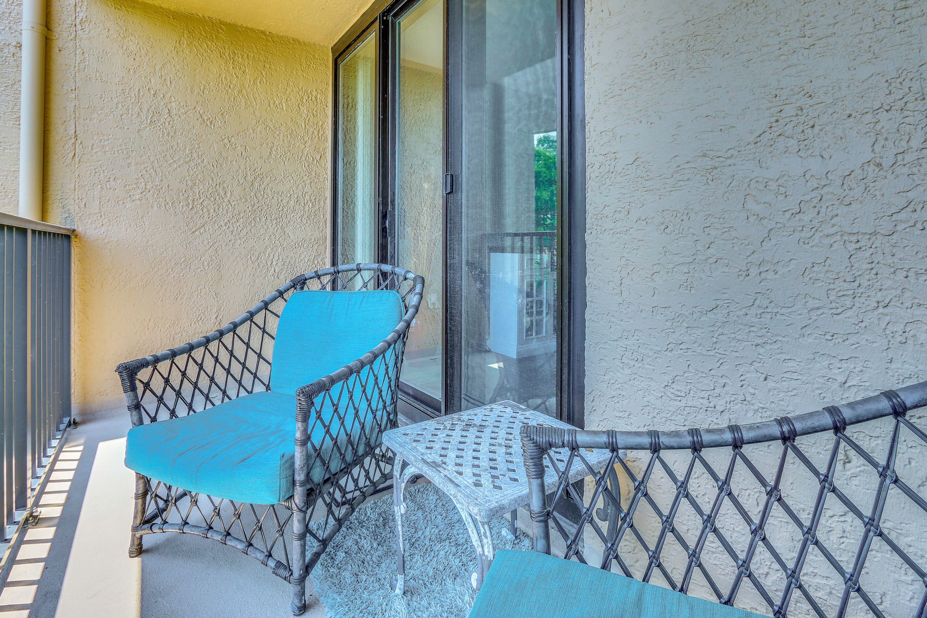 Un balcon avec des meubles en osier, une porte vitrée et un mur à texture.