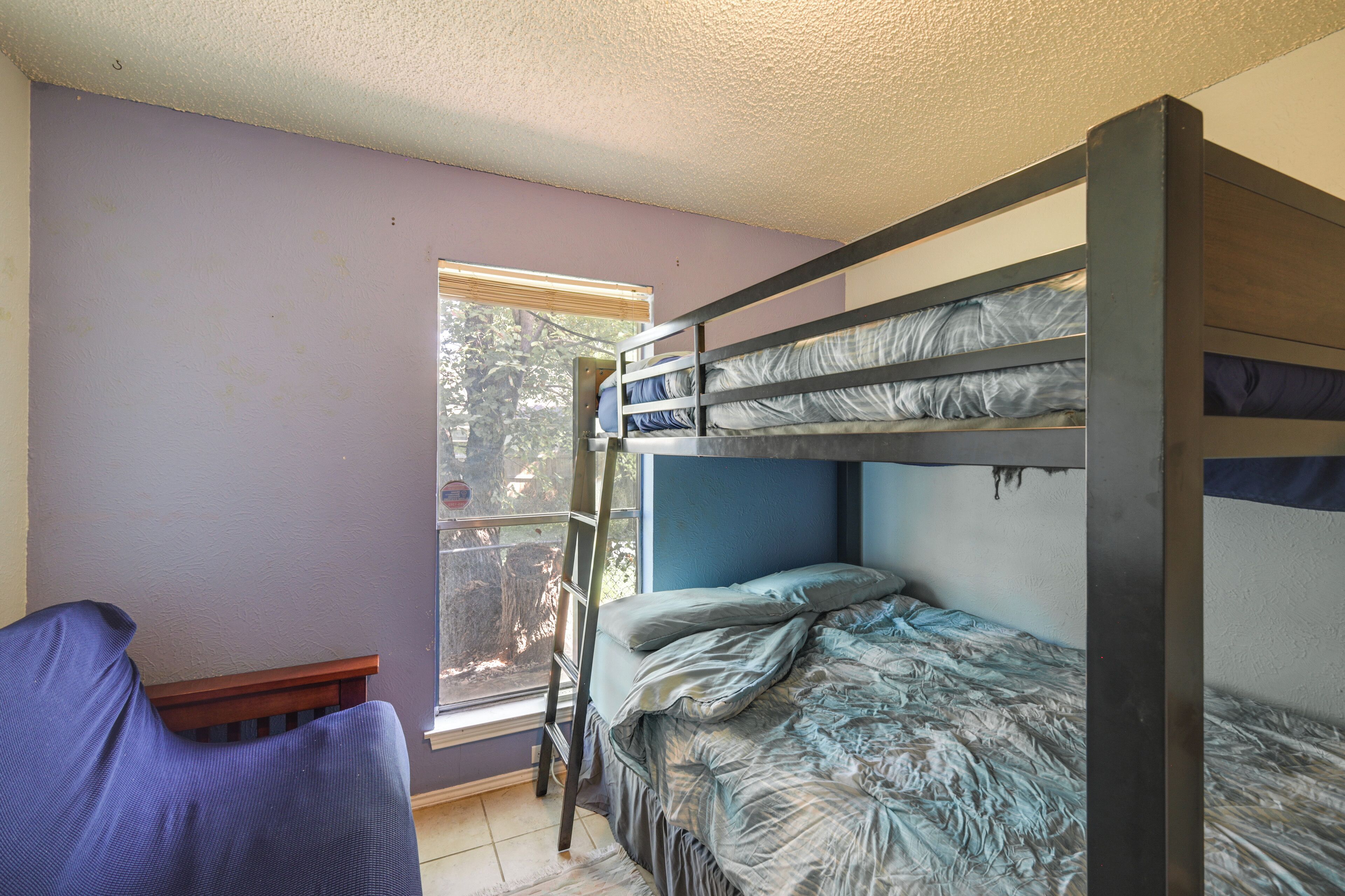 A bunk bed room with a window, a chair, and a ladder.