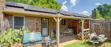 A backyard with a covered patio, a barbecue grill, and a swing chair.
