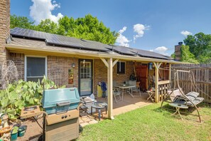 A backyard with a covered patio, a grill, and a swing set. - Walk to At&t Stadium: 2-unit Arlington Duplex! (Arlington)
