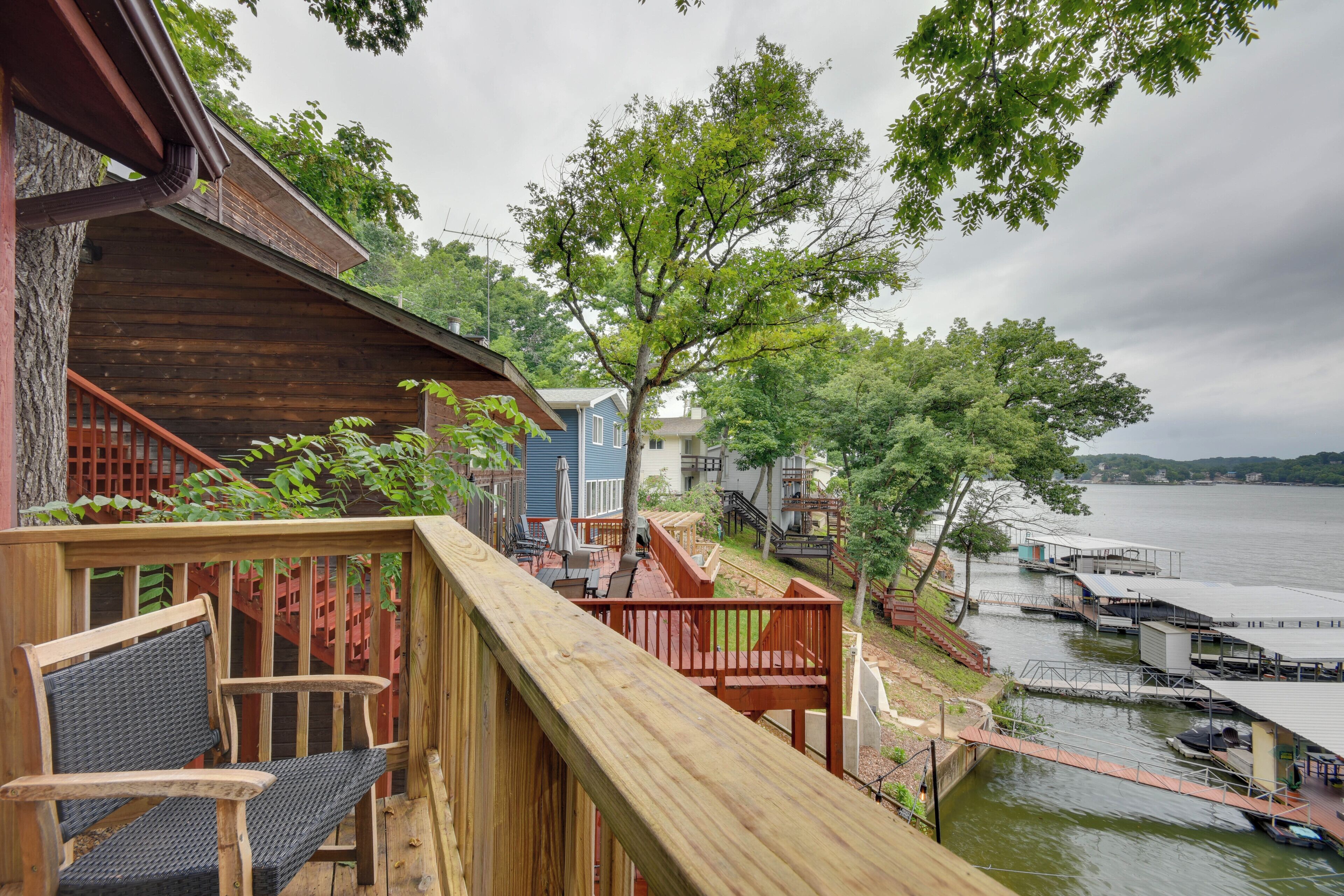 A wooden deck with a chair, a tree, and a view of a lake with docks.