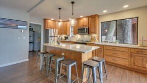 A modern kitchen with wooden cabinets, stainless steel appliances, and a large island with bar stools.