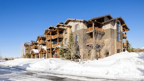 A multi-story building with balconies, stone facade, and snow-covered surroundings. - Gateway to the Teton Valley! Luxe Mtn Condo (Victor)