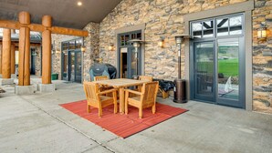 A stone exterior wall, a covered patio with a table and chairs, and a grill. - Gateway to the Teton Valley! Luxe Mtn Condo (Victor)