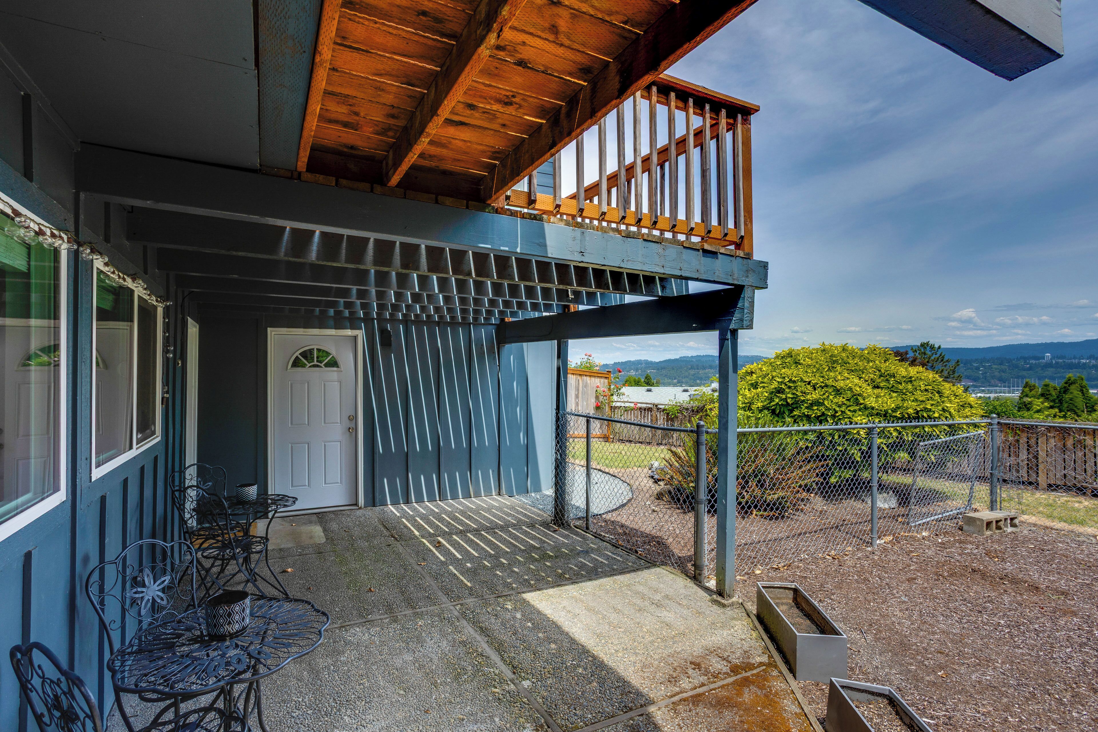 Uma área externa coberta com teto de madeira, cerca de metal e vista para a paisagem.